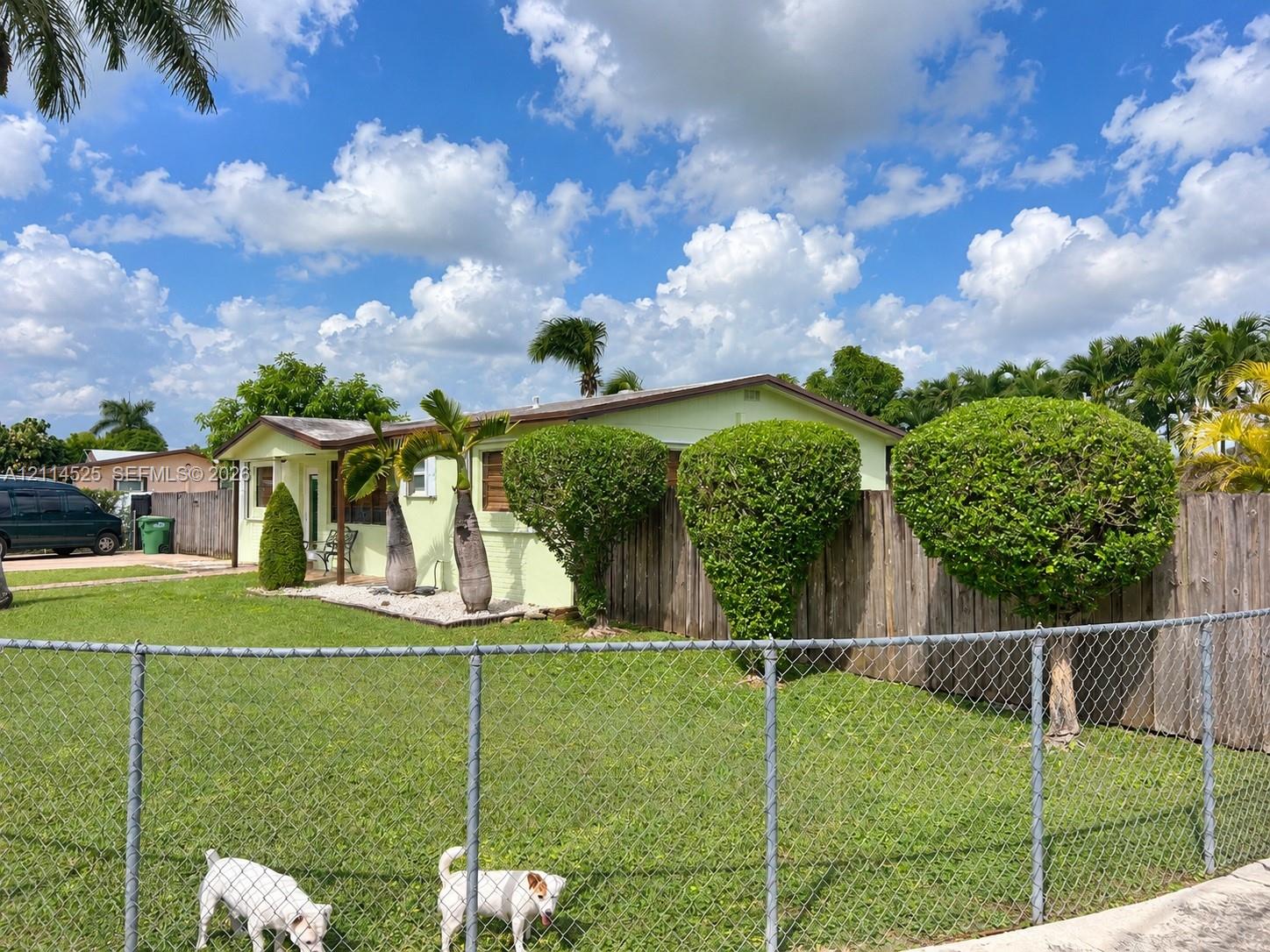 Single-story residence featuring a low-pitch roofline, exterior siding, metal chain-link perimeter fencing, and mature landscaping Single-story residence featuring a low-pitch roofline, exterior siding, metal chain-link perimeter fencing, and mature landscaping