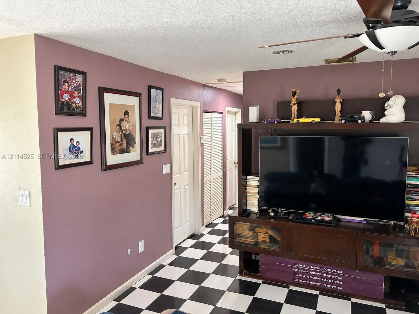 Checkered tile flooring, ceiling fan with integrated lighting, and interior six-panel doors