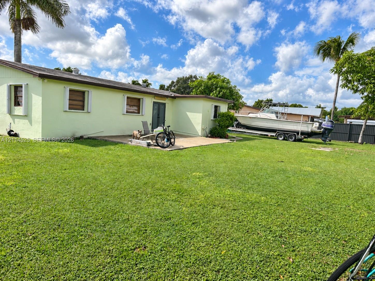 Expansive backyard featuring a large grass lawn, a paved patio, and perimeter fencing