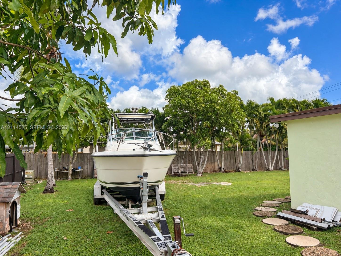 Expansive backyard featuring a level lawn, perimeter wood fencing, and mature trees with stone paver accents Expansive backyard featuring a level lawn, perimeter wood fencing, and mature trees with stone paver accents