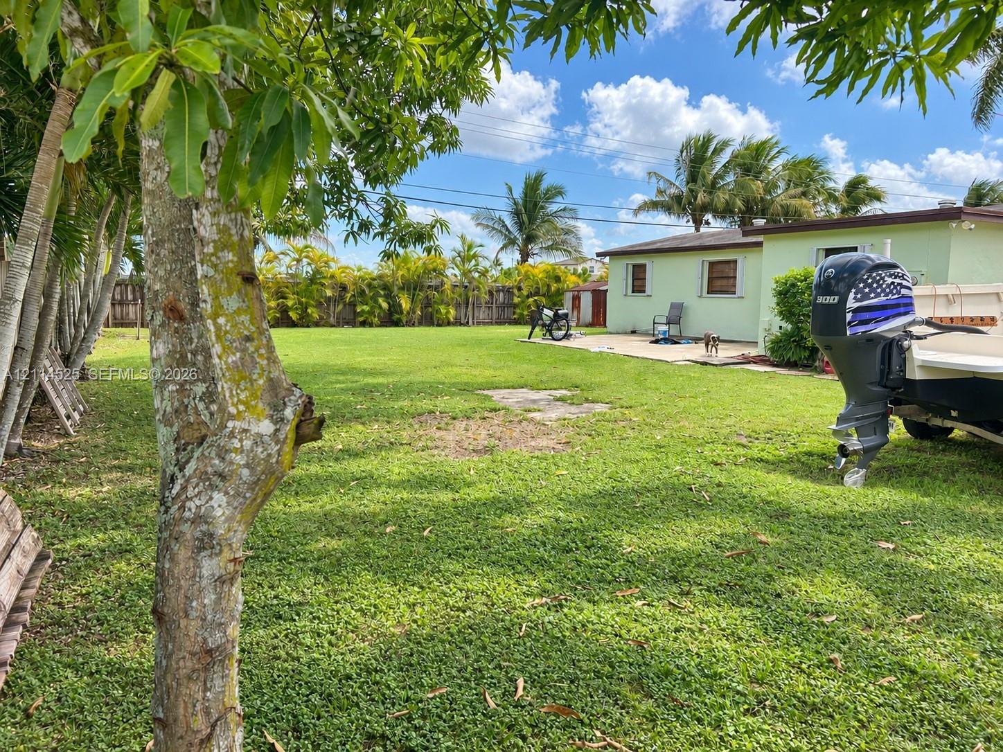Expansive backyard featuring a concrete patio, perimeter fencing, mature trees, and established landscaping Expansive backyard featuring a concrete patio, perimeter fencing, mature trees, and established landscaping