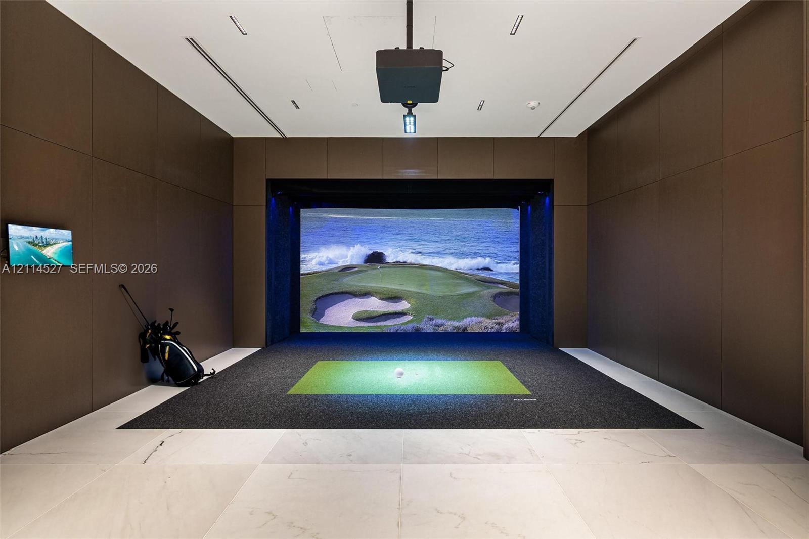Recreation room featuring floor-to-ceiling wood-paneled walls, large-format tile flooring, a recessed ceiling projector, and a built-in digital sports simulation screen
