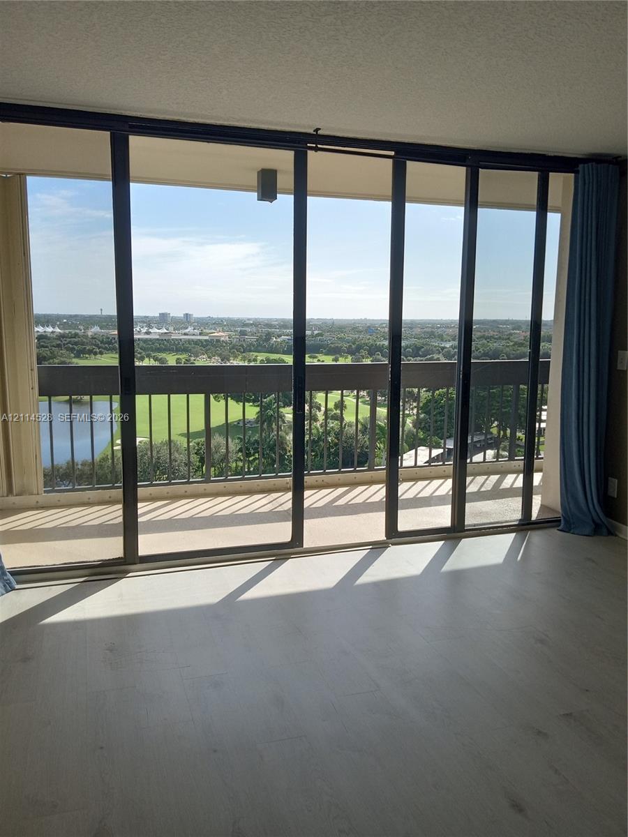 Floor-to-ceiling sliding glass doors opening to a private balcony with metal railing, wood-finish flooring, and expansive natural scenery