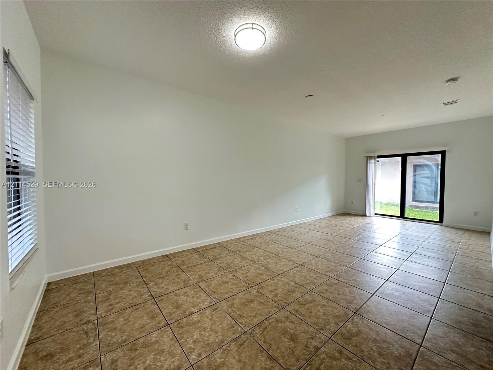 Ceramic tile flooring, neutral wall finishes, flush-mount ceiling lighting, and sliding glass doors