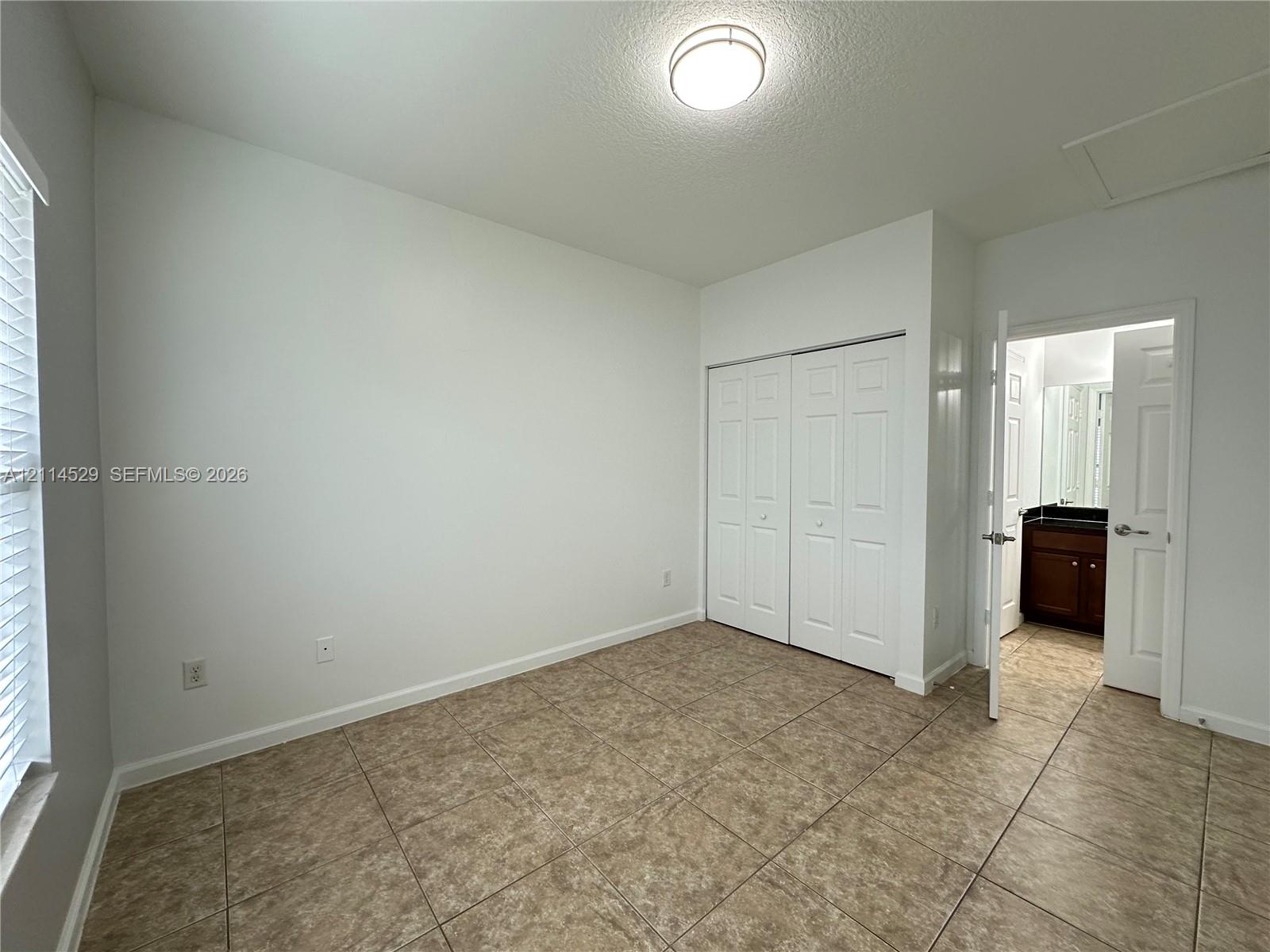 Room featuring ceramic tile flooring, double-door closet, recessed lighting fixture, and window with blinds