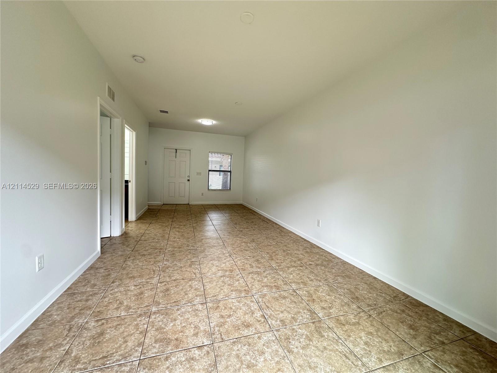 Open interior space featuring light-toned tile flooring, recessed lighting, and a neutral color palette