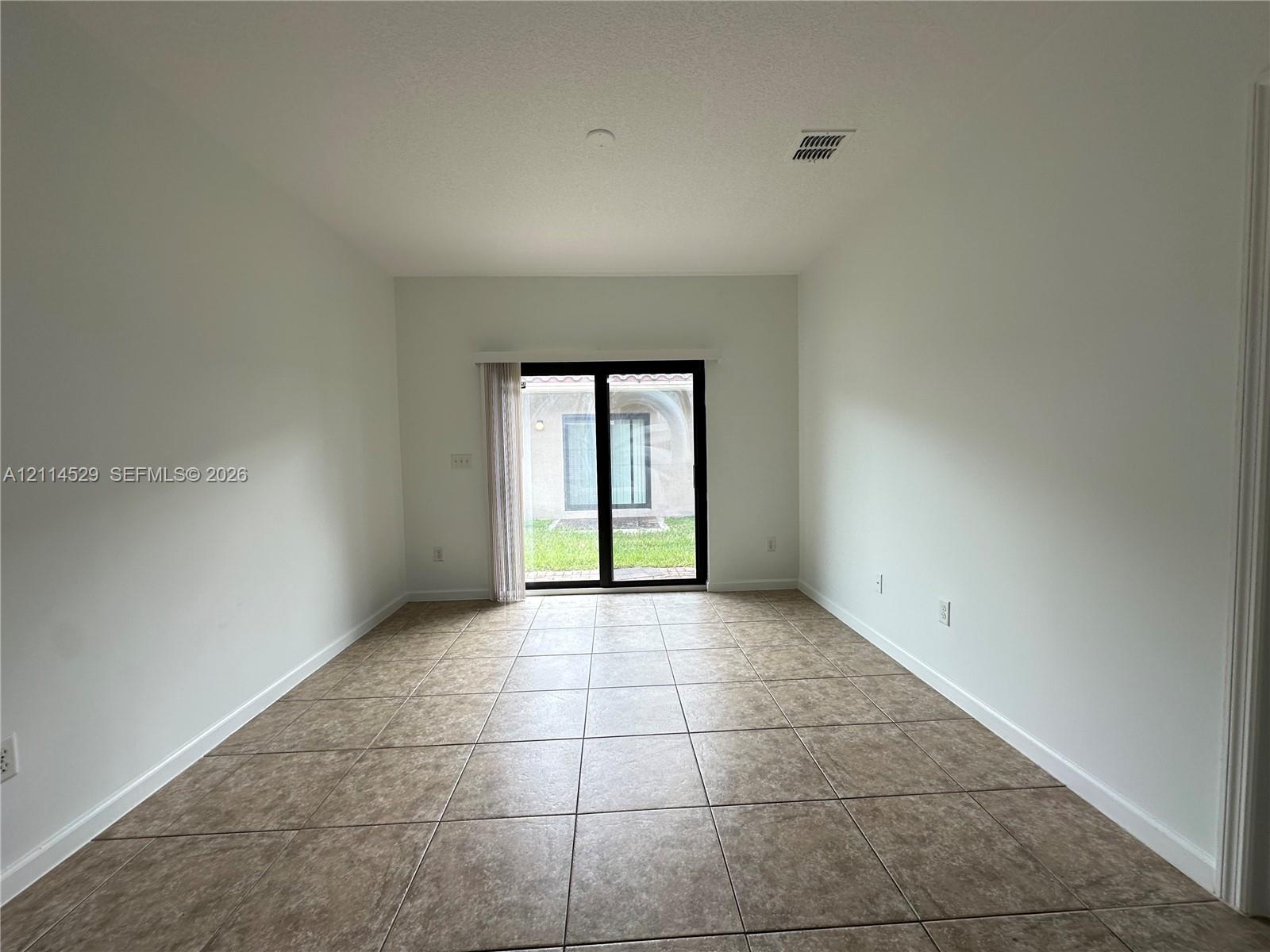 Interior space featuring neutral wall tones, large-format tile flooring, and black-framed sliding glass doors