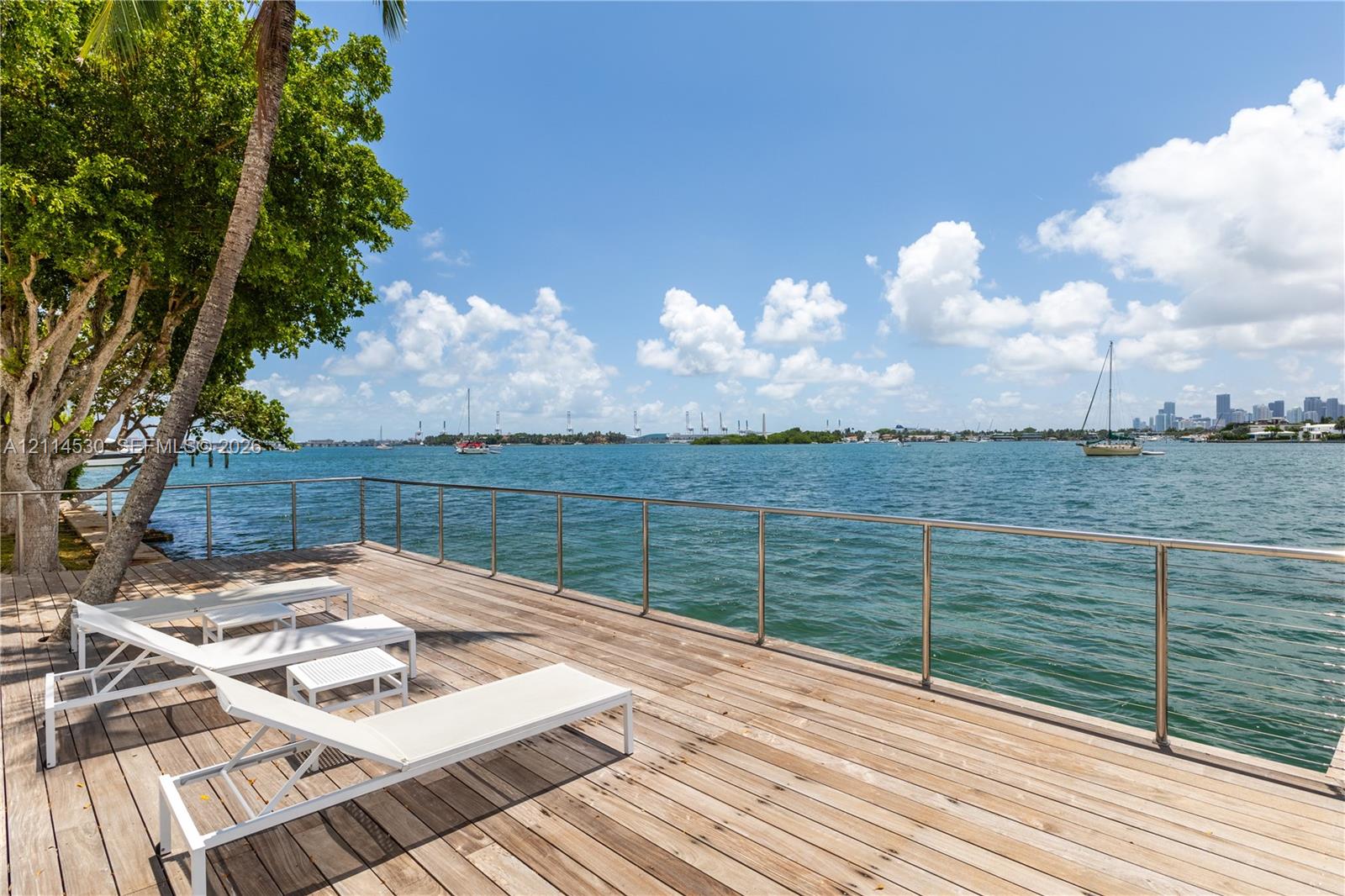 Waterfront wood deck featuring stainless steel railings and mature trees
