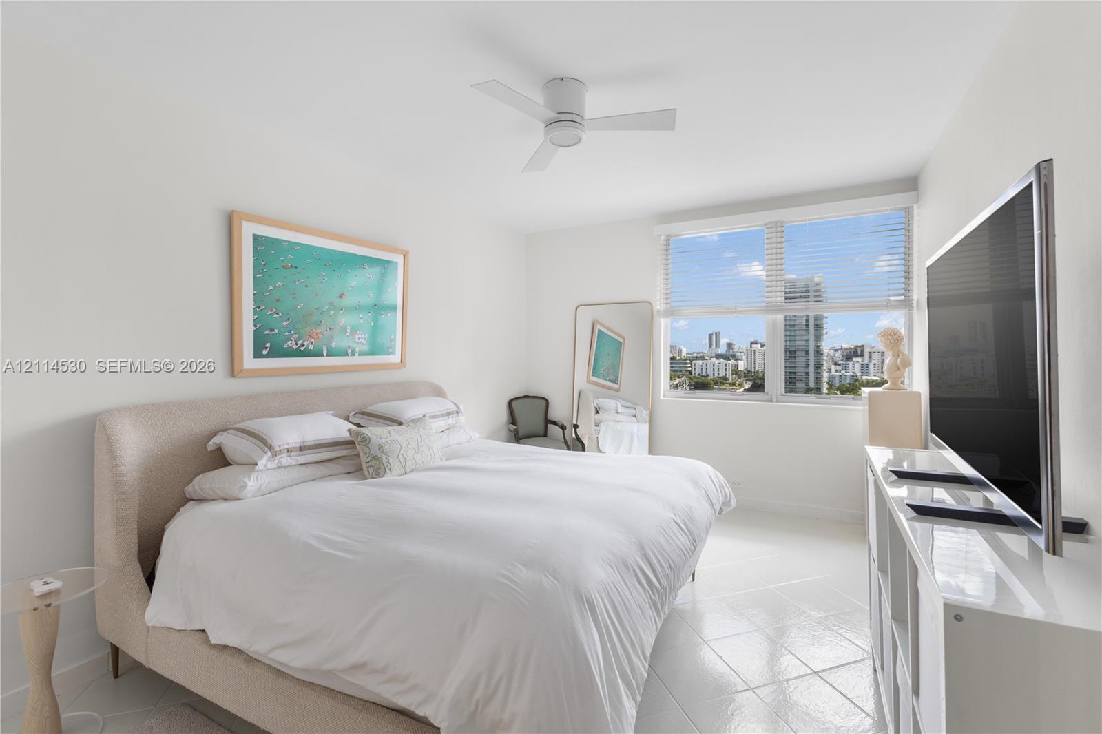 Bright room featuring large-format tile flooring, white-finish ceiling fan, and expansive window with horizontal blinds