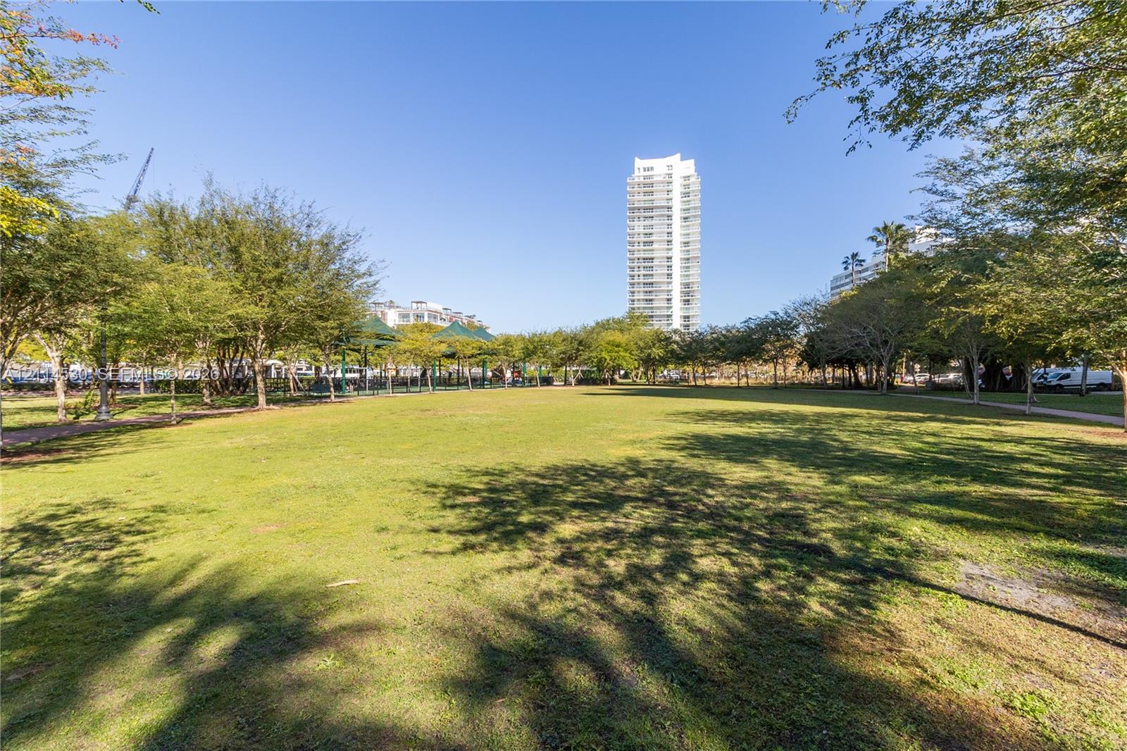 Expansive green space featuring mature trees and paved pedestrian paths