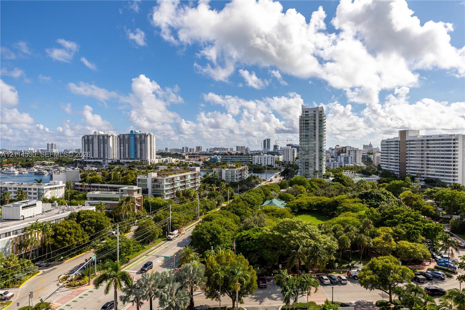 Panoramic cityscape featuring dense tree canopy, waterfront boat slips, and multiple high-rise buildings