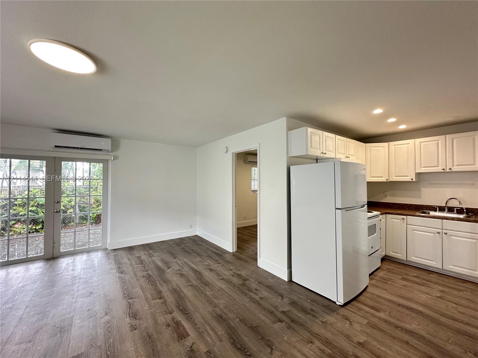 Kitchen featuring white shaker-style cabinetry, wood-finish flooring, recessed lighting, and a glass-paneled exterior door Kitchen featuring white shaker-style cabinetry, wood-finish flooring, recessed lighting, and a glass-paneled exterior door