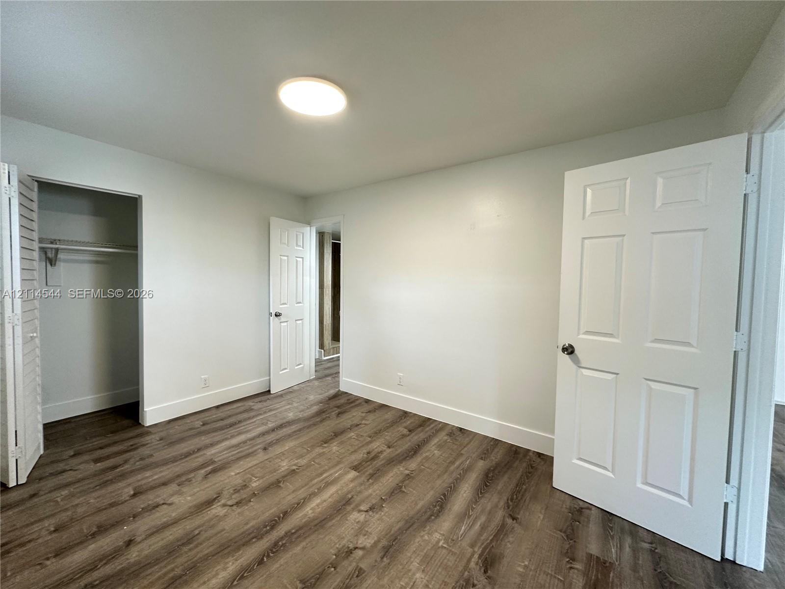 Interior space featuring wood-finish flooring, six-panel interior doors, and a closet with louvered double doors