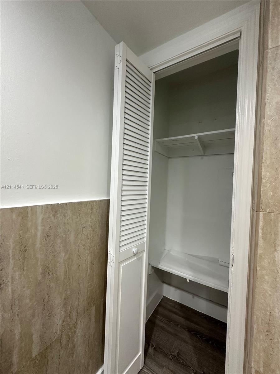 Closet featuring white louvered bi-fold doors, interior shelving, and wood-finish flooring