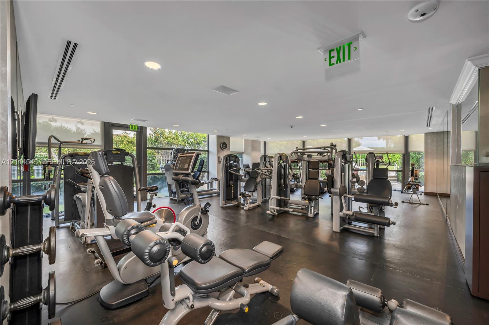 Fitness center featuring rubberized flooring, mirrored walls, recessed lighting, and expansive floor-to-ceiling windows