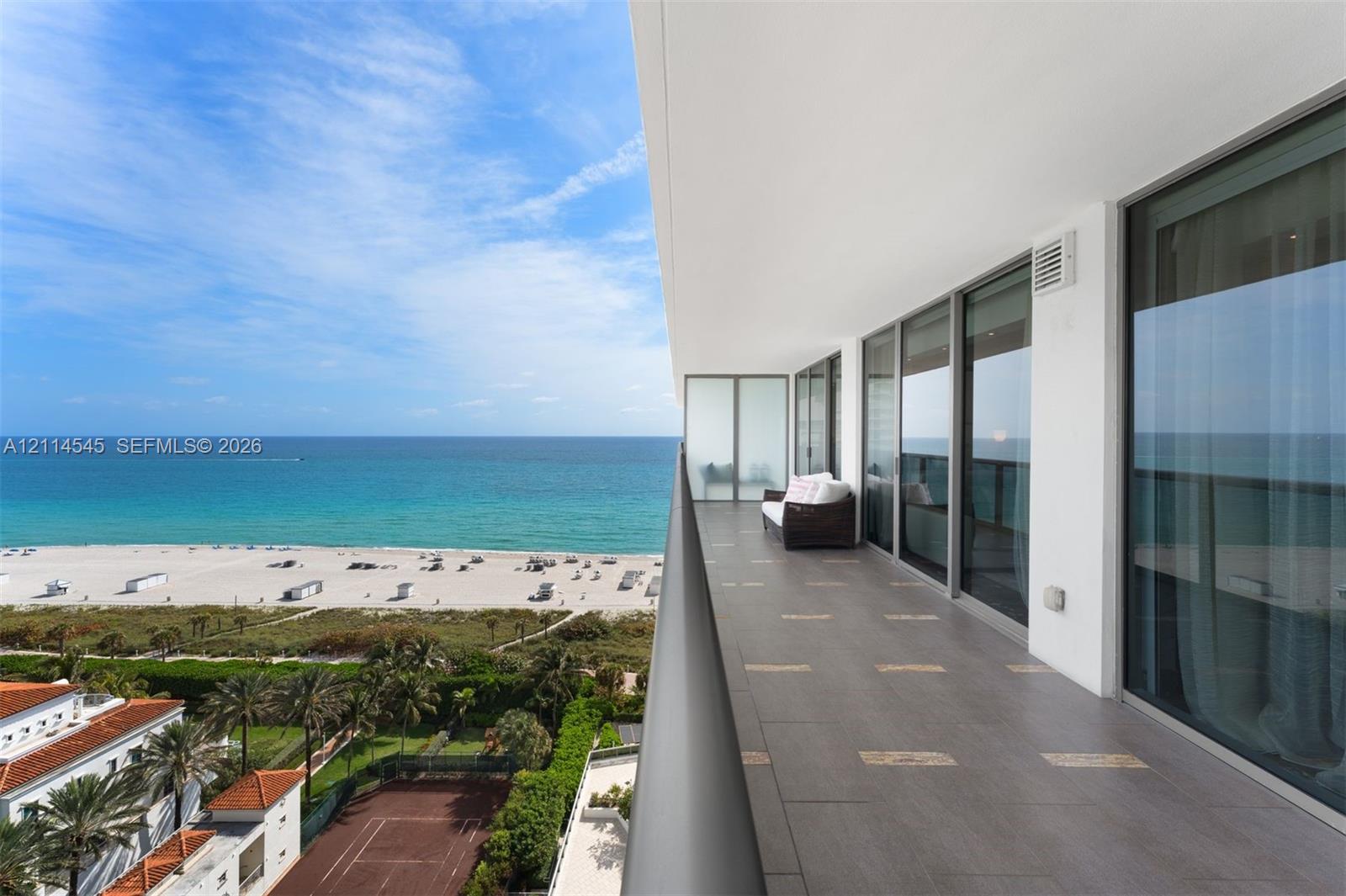 Expansive balcony with large-format tile flooring, metal railing, and floor-to-ceiling glass sliding doors