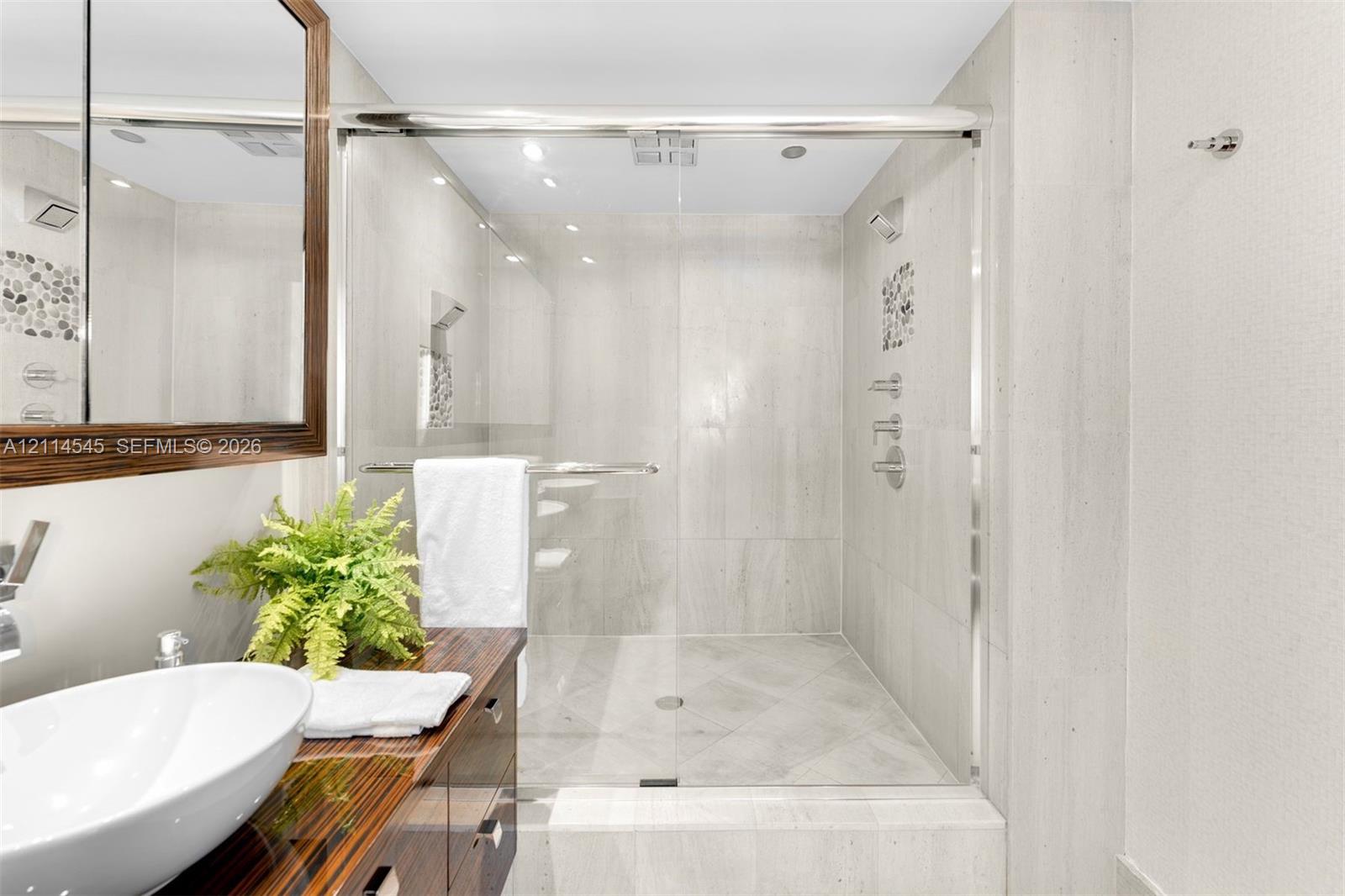 Walk-in shower featuring glass sliding doors, large-format tile surround, and mosaic tile accents