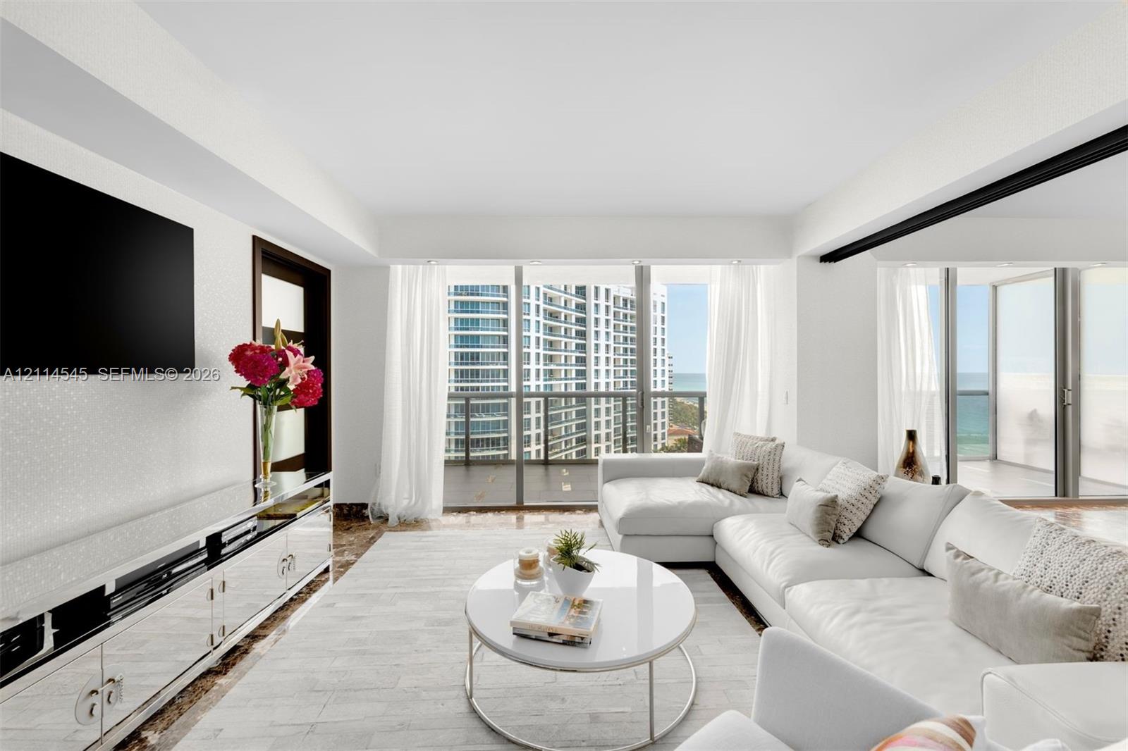 Open-concept living area featuring floor-to-ceiling glass windows, polished stone flooring, and a private balcony