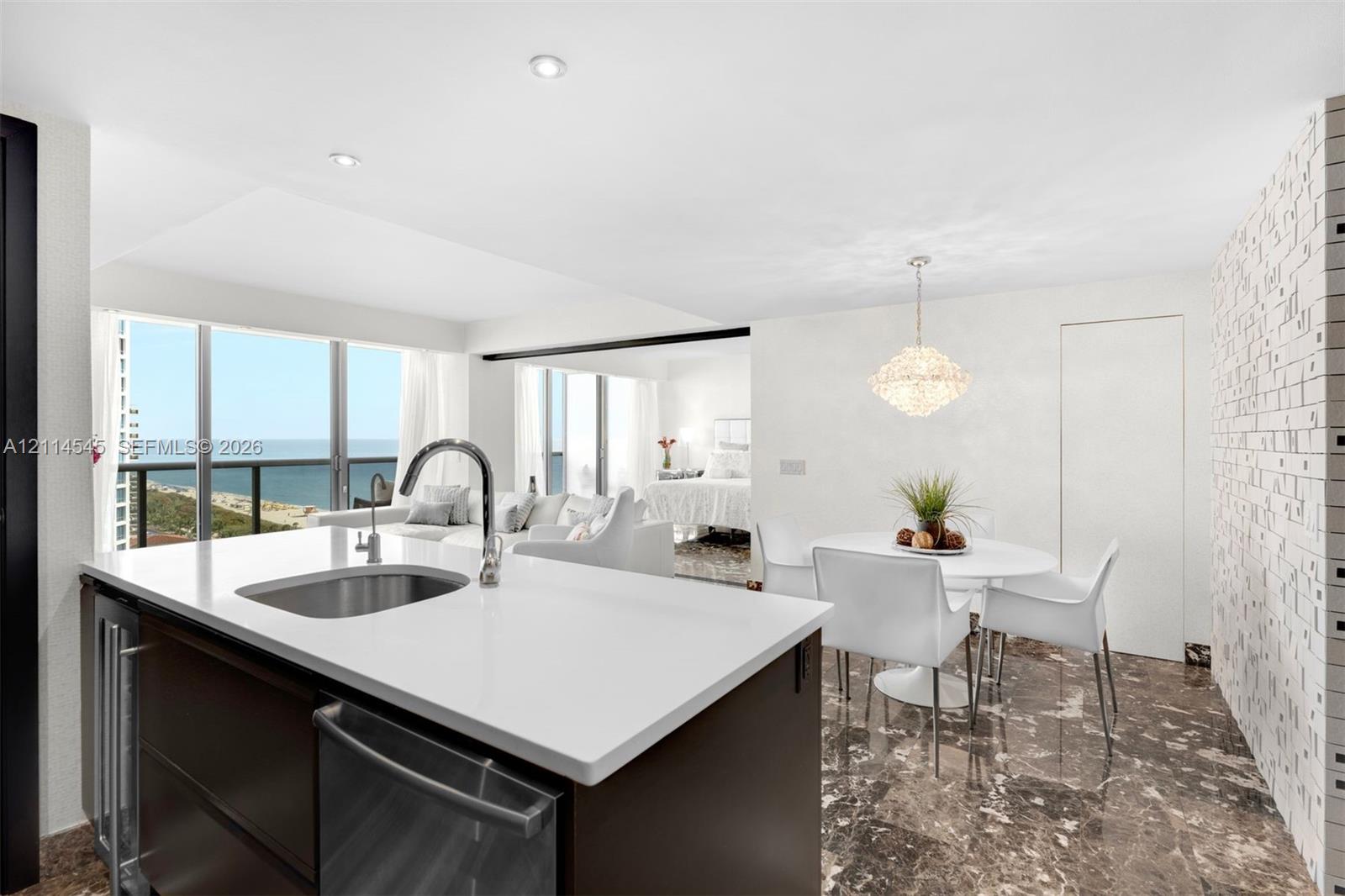 Kitchen island featuring a stone countertop, under-mount stainless steel sink, and sleek cabinetry