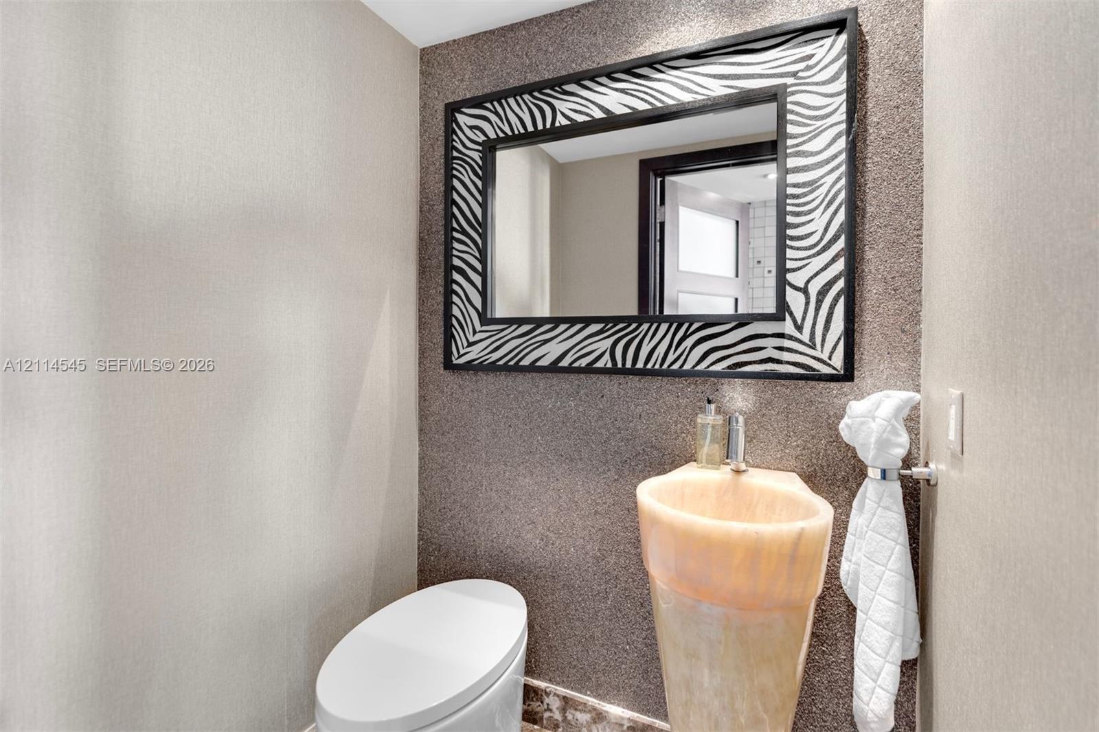 Textured wall finish, pedestal sink with integrated basin, and rectangular wall mirror