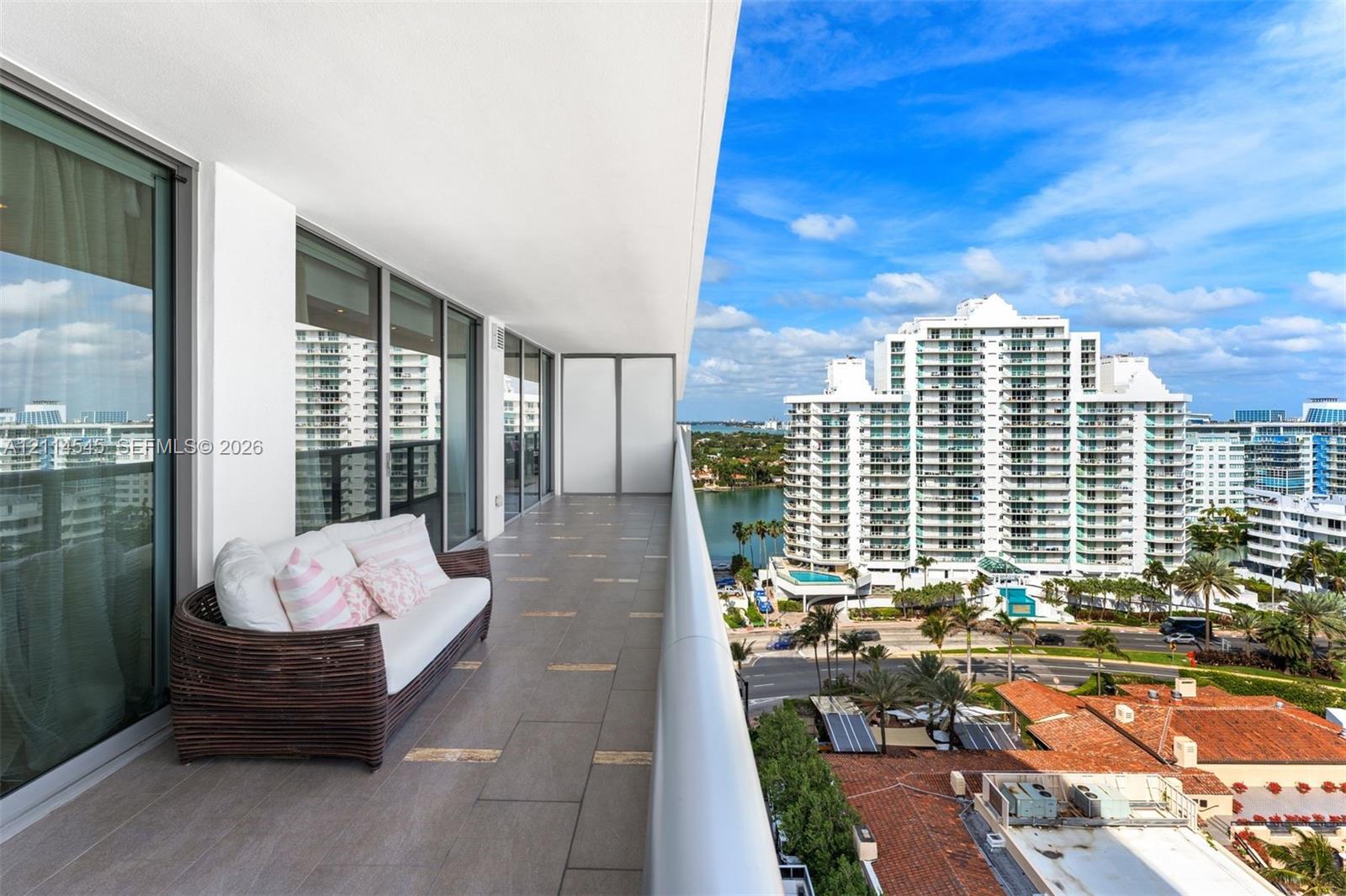 Expansive covered balcony featuring large-format ceramic tile flooring, a minimalist metal railing, and floor-to-ceiling glass sliding doors