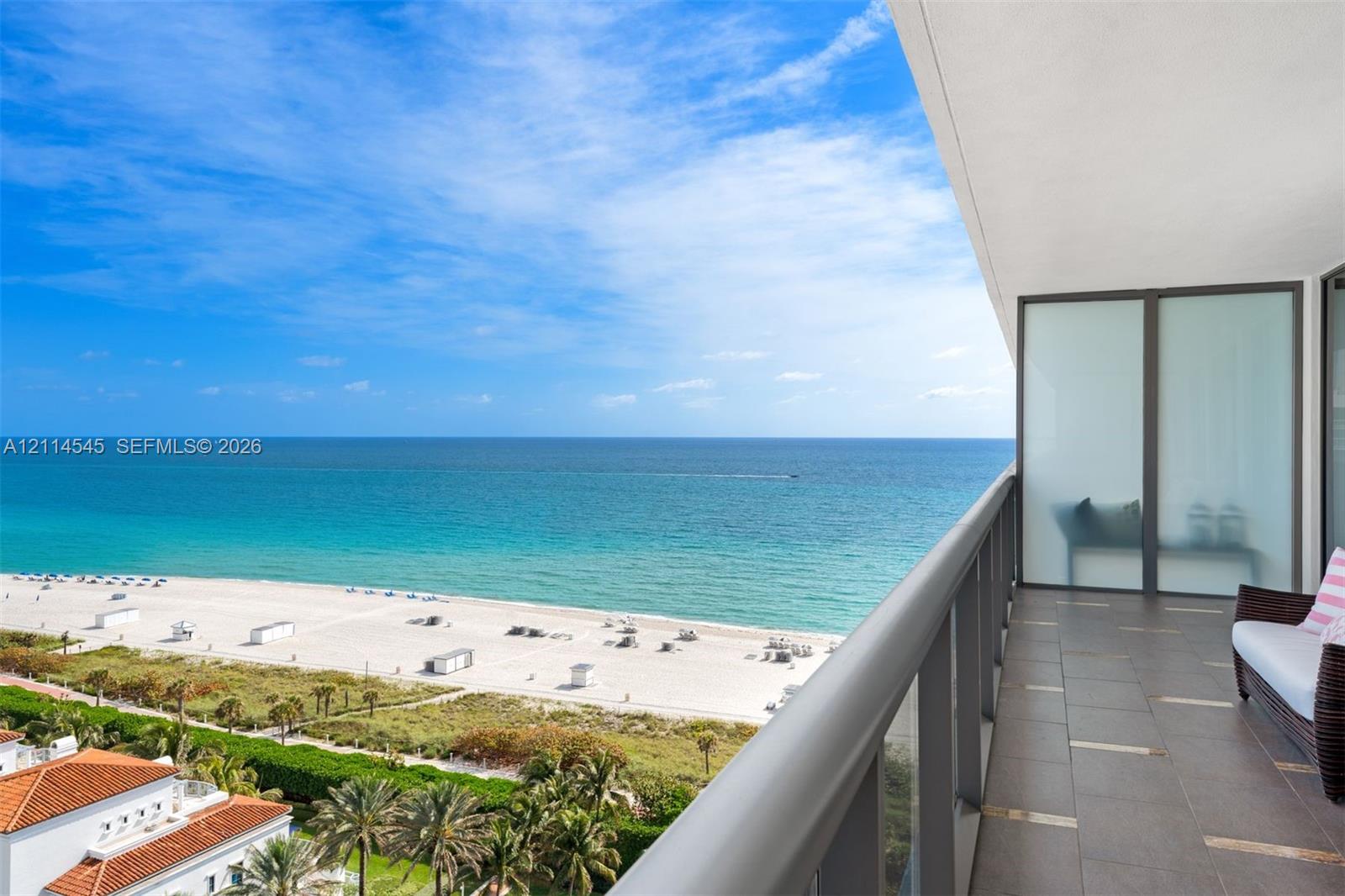 Covered balcony featuring tile flooring, metal railings, and frosted glass privacy screening