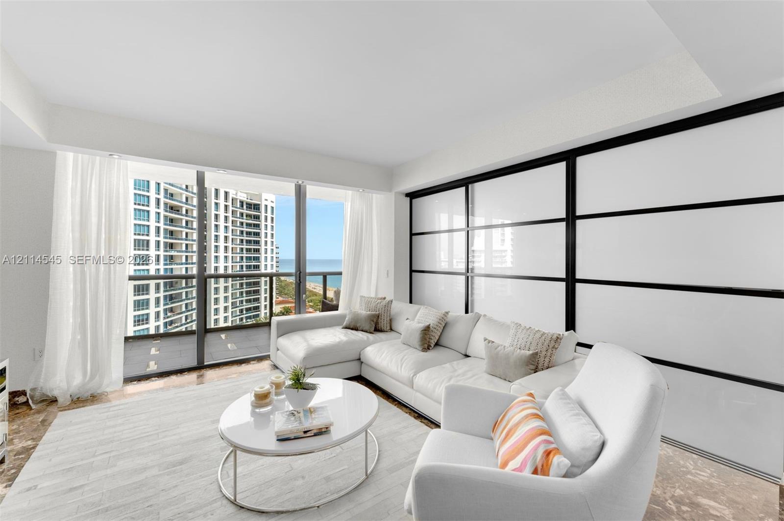 Floor-to-ceiling windows, oversized sliding glass balcony door, and large-format sliding wall panels with black metal framing