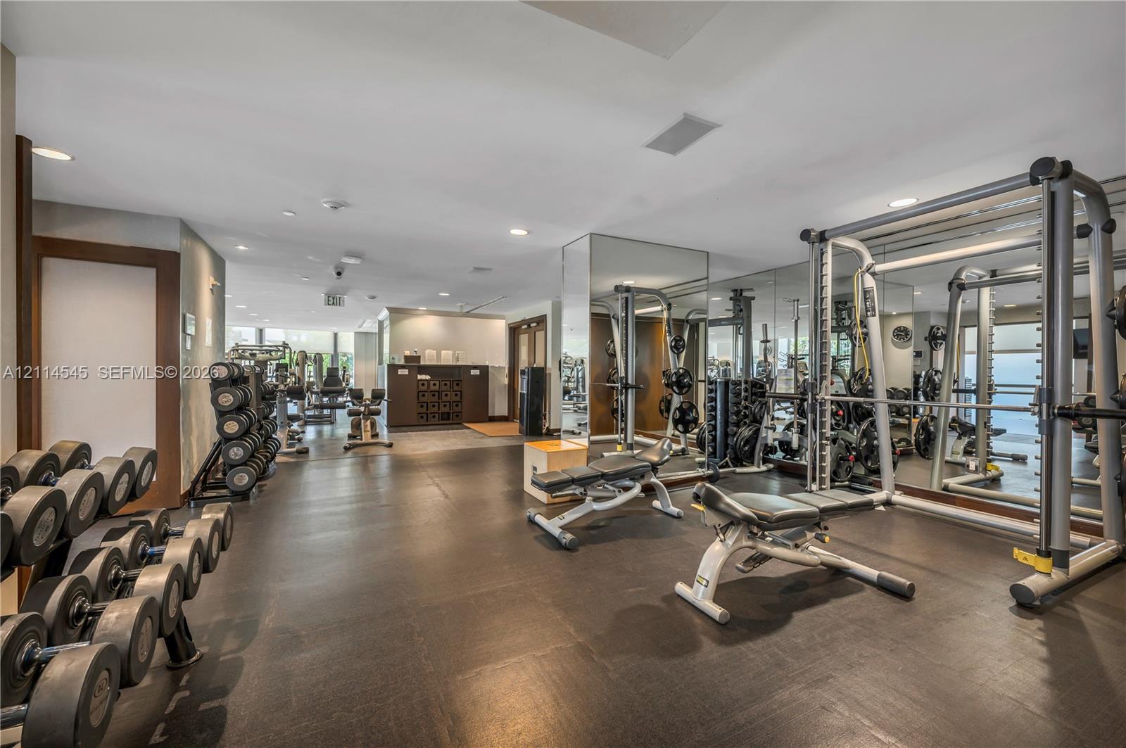 Fitness center featuring rubberized flooring, mirrored walls, recessed lighting, and wall-to-wall windows