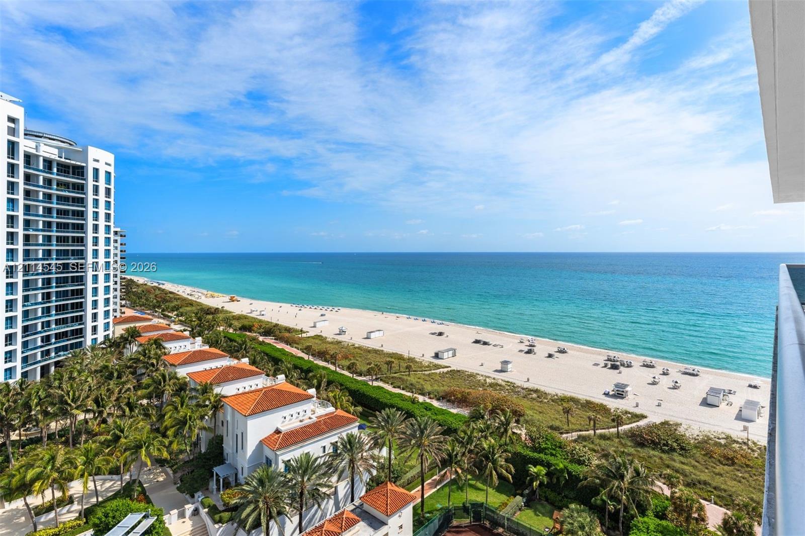 Panoramic coastal scenery featuring a direct expanse of ocean, white sand beach, tropical palm landscaping, and high-rise architecture
