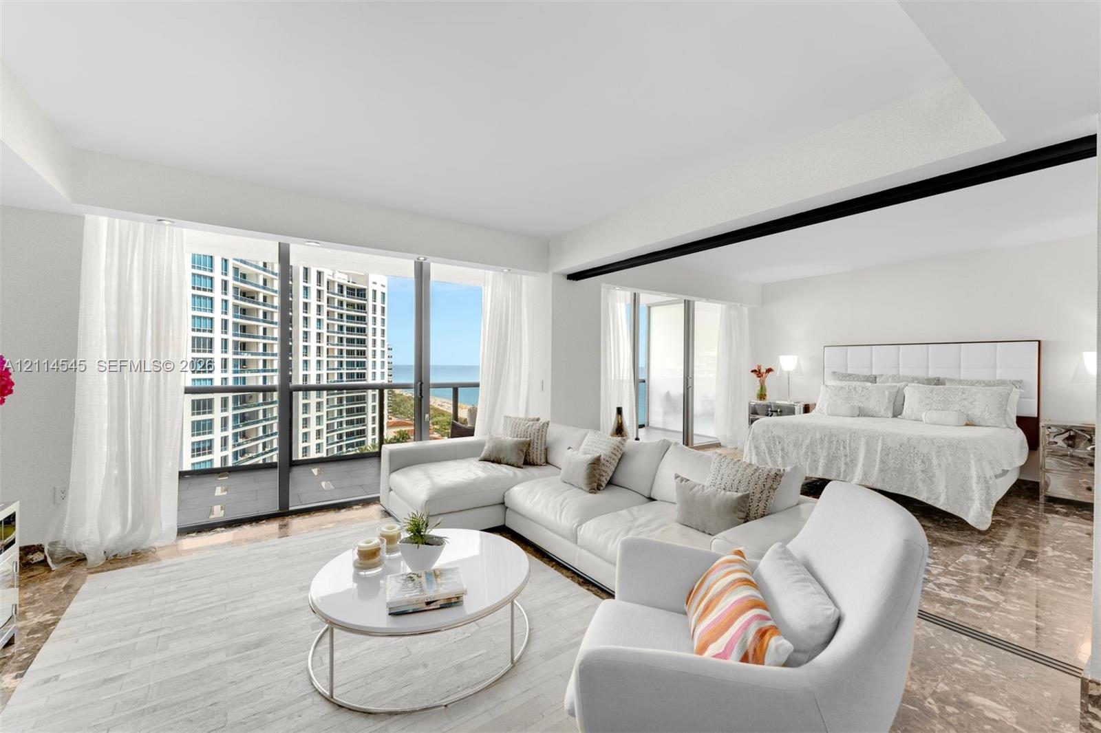 Floor-to-ceiling windows with coastal exposure, polished stone flooring, recessed ceiling lighting, and private balconies with glass railings