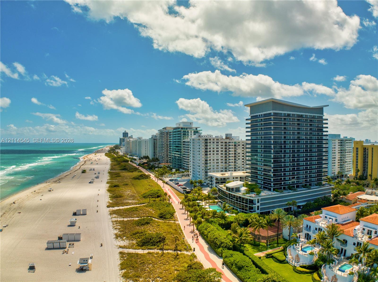 High-rise coastal property featuring expansive oceanfront access, direct beach proximity, mature tropical landscaping, and a multi-level structural design