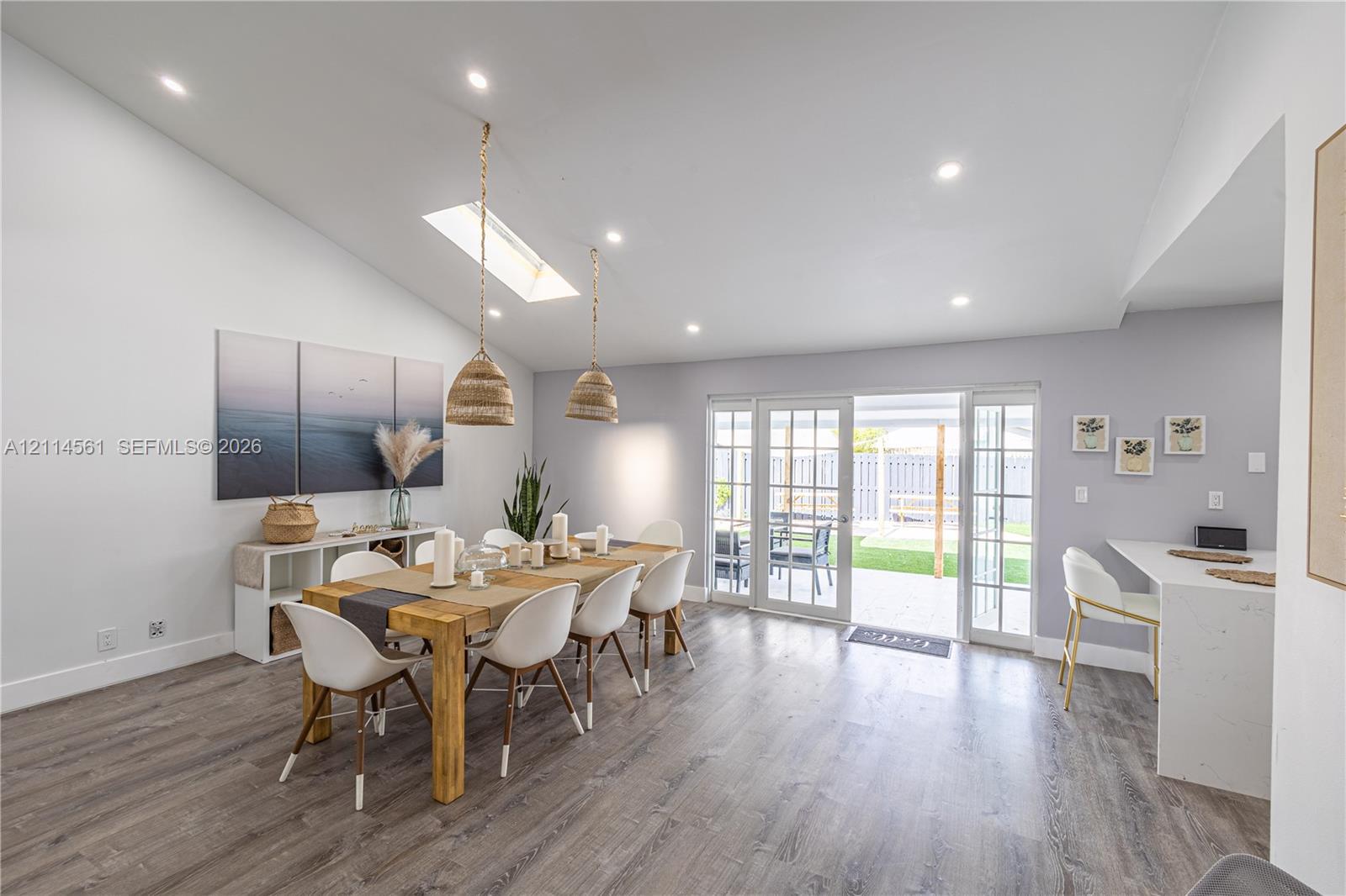 Vaulted ceiling with skylight, recessed lighting, wood-finish flooring, and white glass-pane French doors
