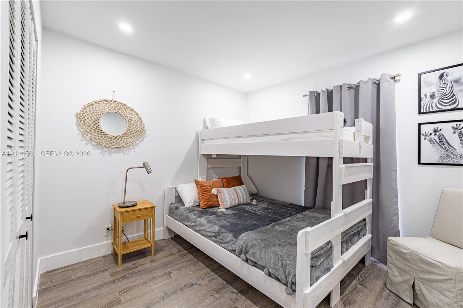 Room interior featuring wood-finish flooring, recessed lighting, and a closet with louvered doors