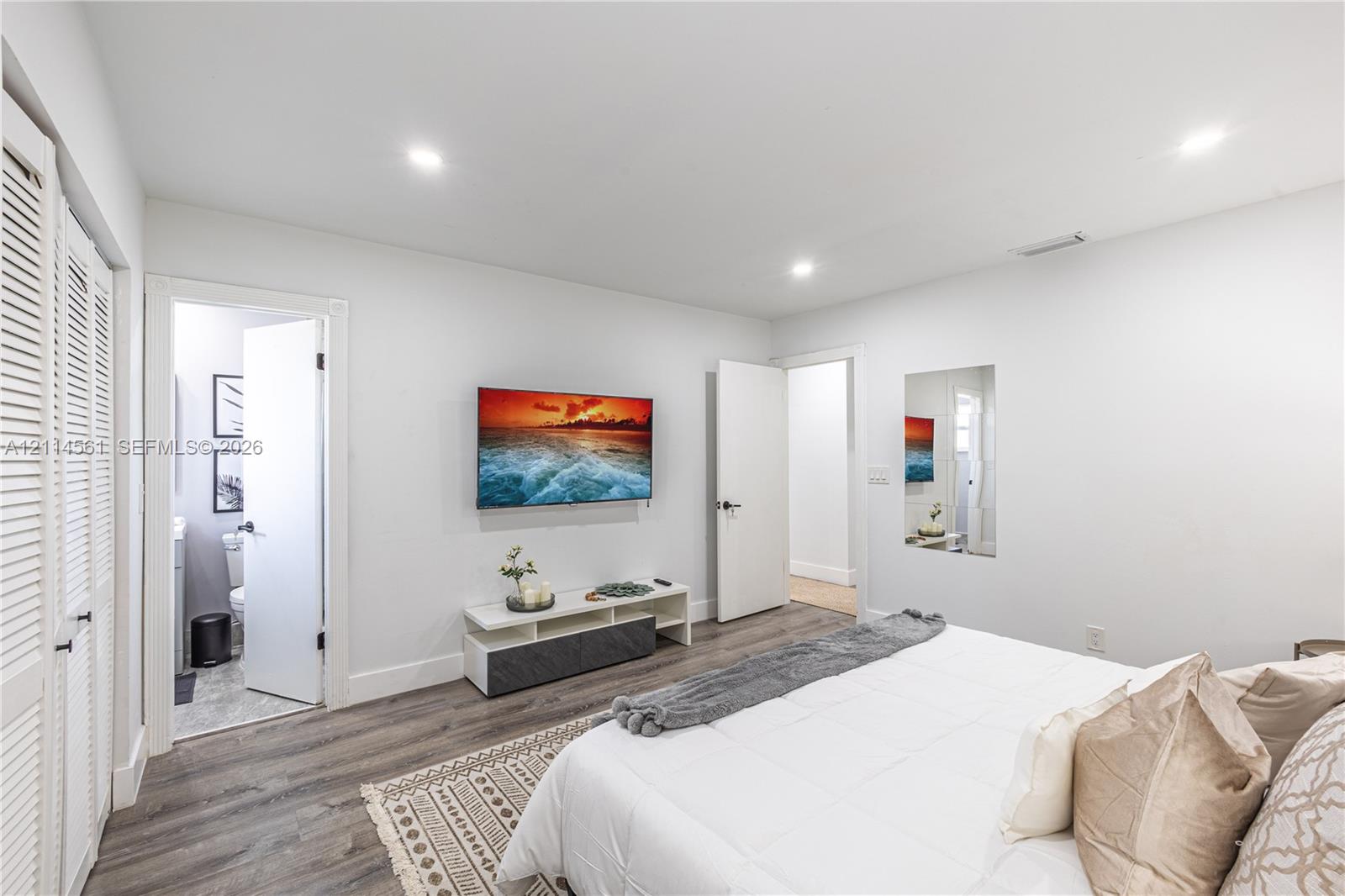 Recessed ceiling lighting, wood-finish flooring, and white louvered closet doors