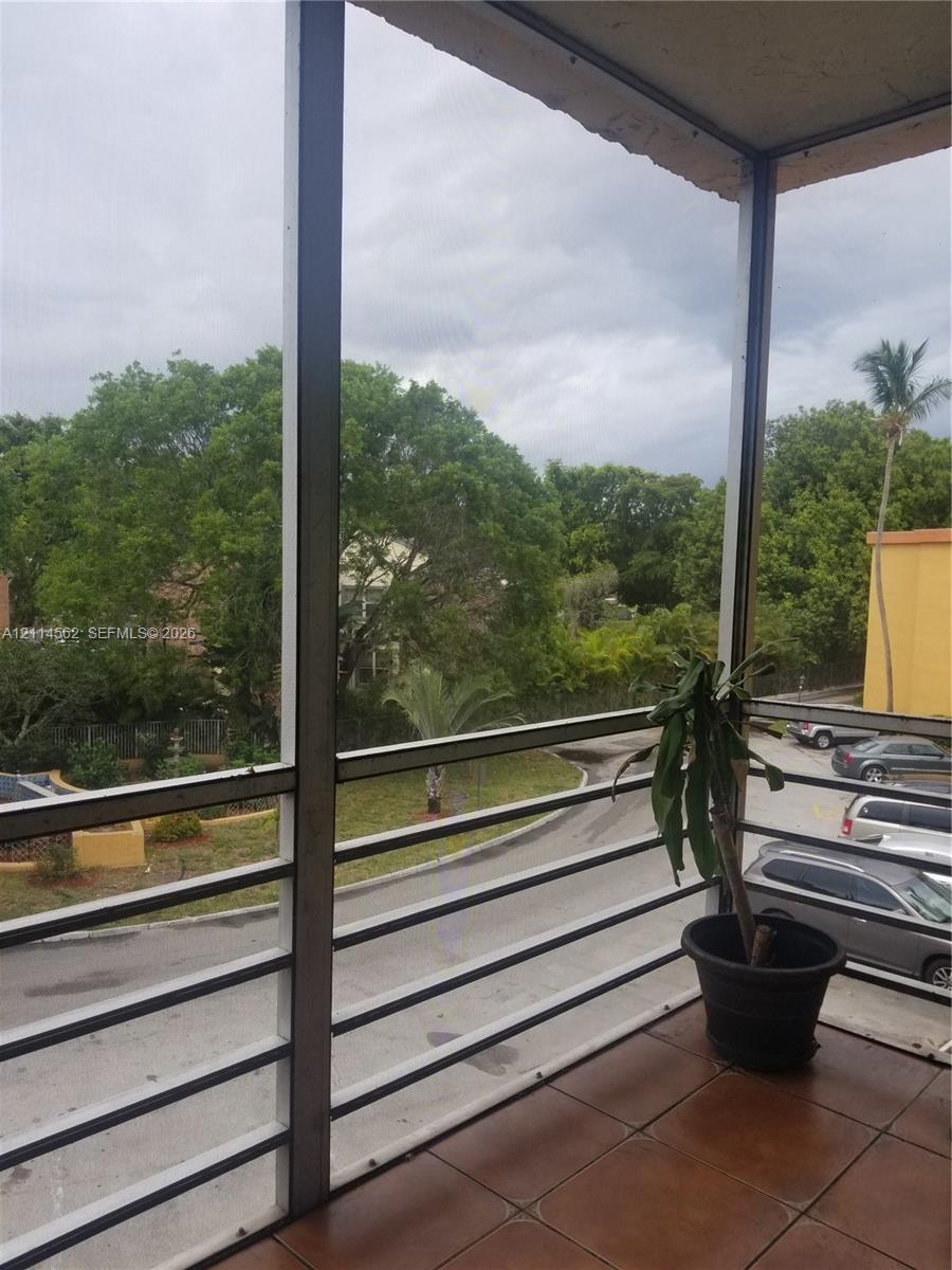 Screened balcony featuring ceramic tile flooring and a metal railing
