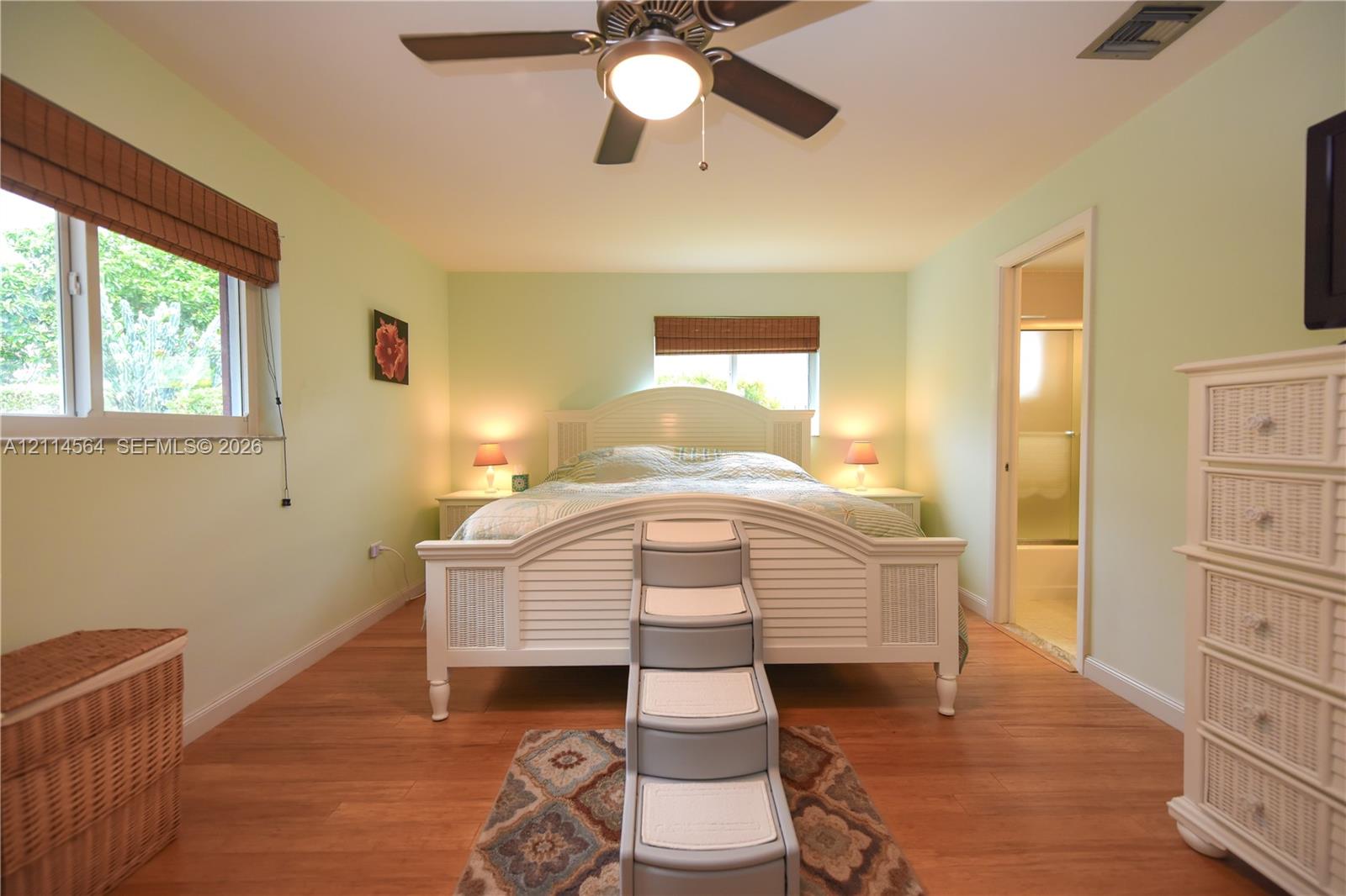 Wood-finish flooring, multi-pane windows with integrated blinds, and a ceiling fan with integrated lighting