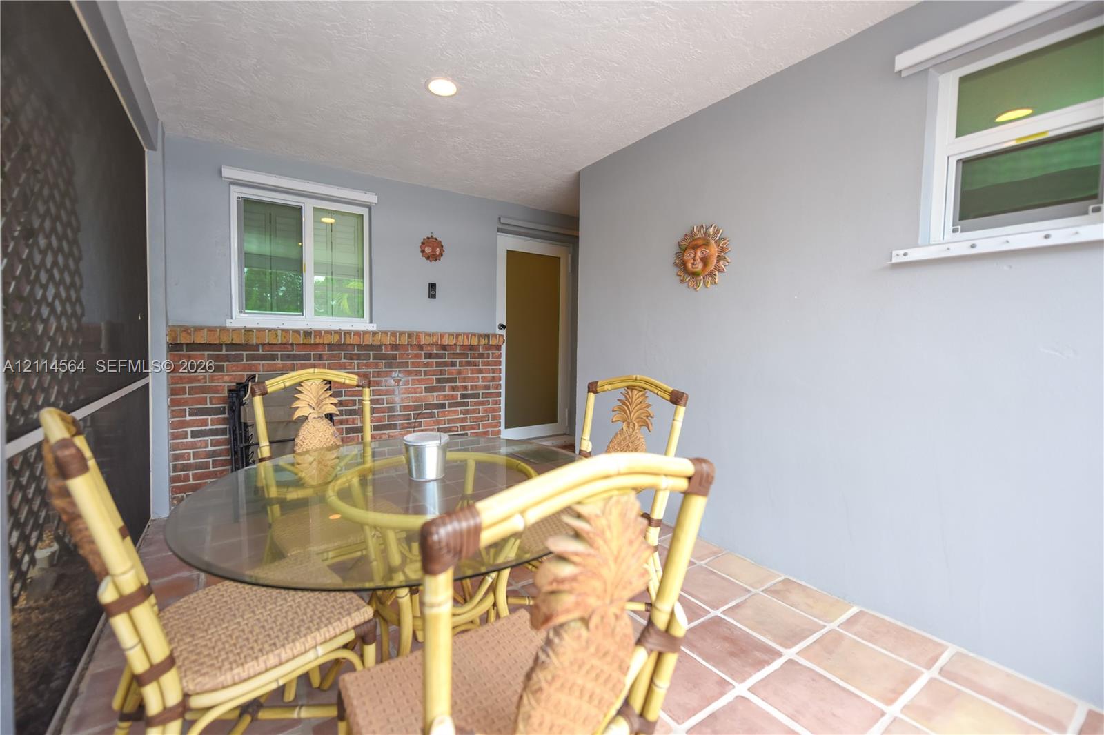 Enclosed porch featuring ceramic tile flooring, a red brick half-wall, recessed lighting, and white-framed sliding windows