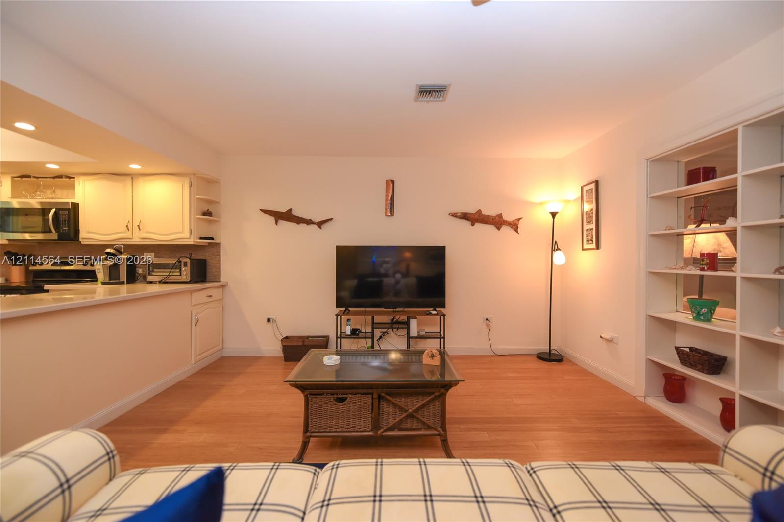 Wood-finish flooring, recessed lighting, and built-in white shelving unit