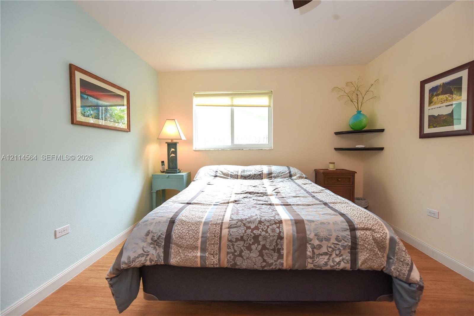 Room featuring wood-finish flooring, a horizontal sliding window, and dual wall-mounted floating shelves