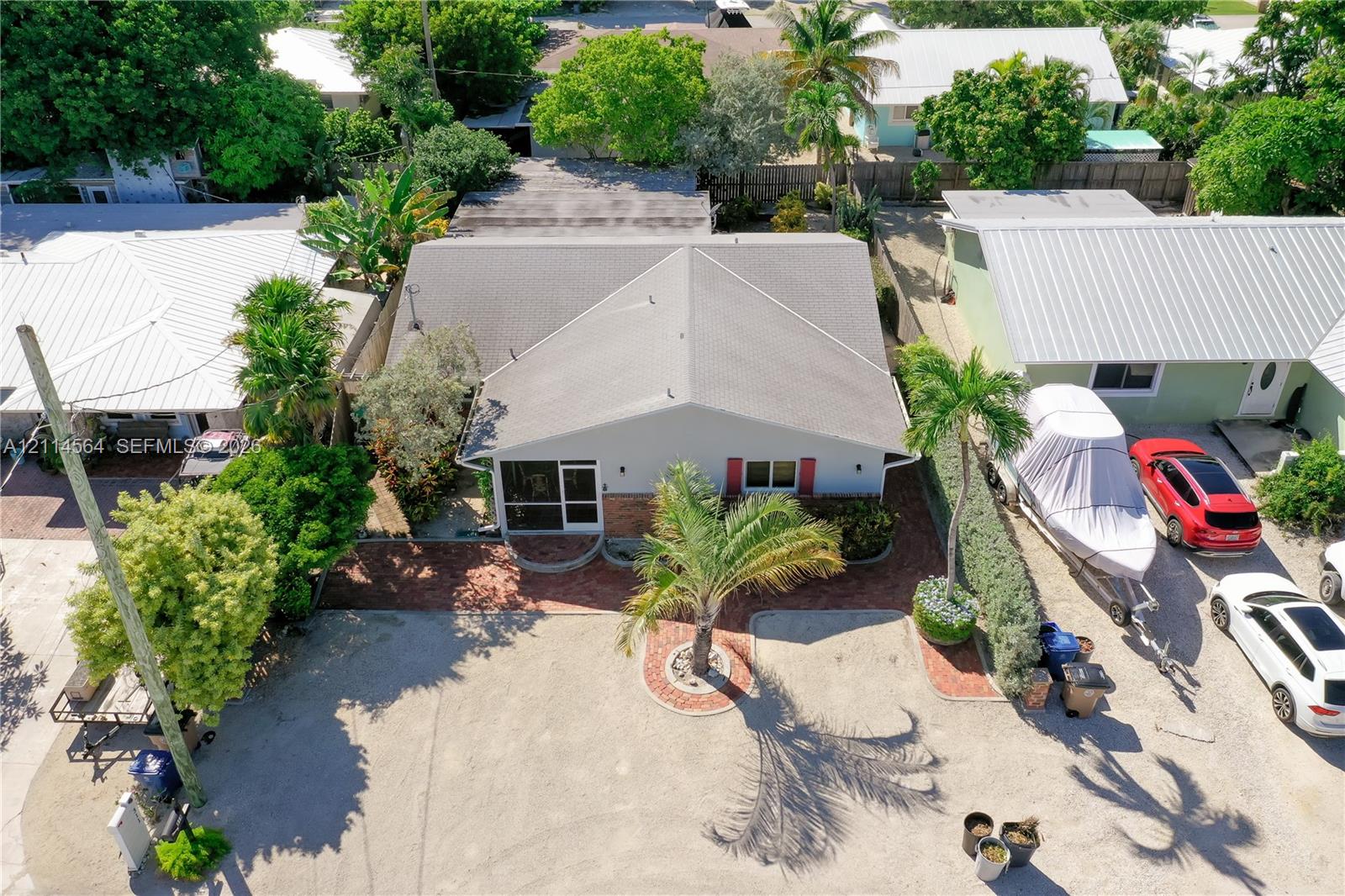 Single-story residence featuring a hipped roof, masonry exterior, brick-accented hardscaping, and mature palm landscaping