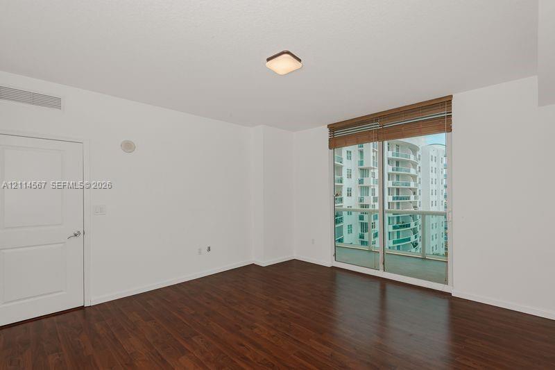 Interior space featuring wood-finish flooring, full-height sliding glass doors, horizontal window blinds, and a flush-mount ceiling light fixture