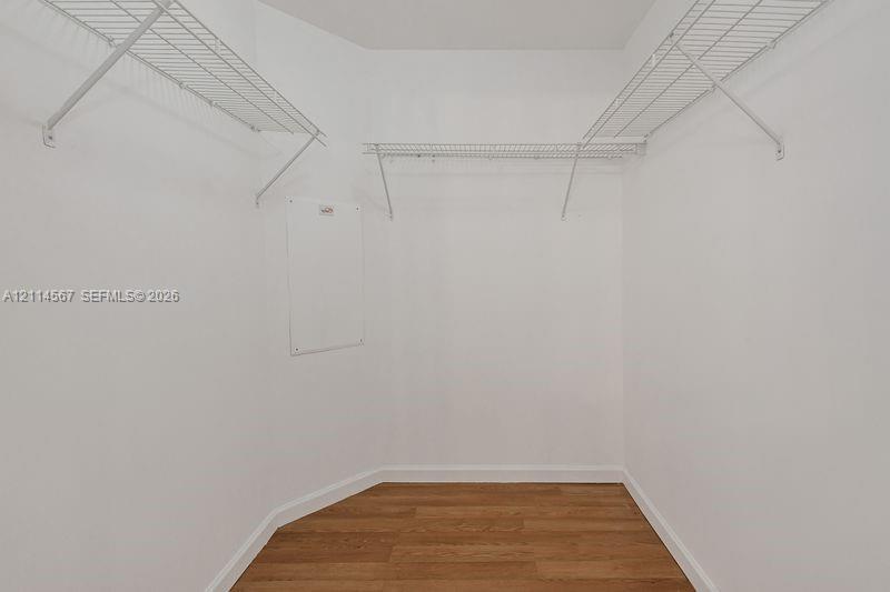 Storage space featuring wood-finish flooring and installed white wire shelving
