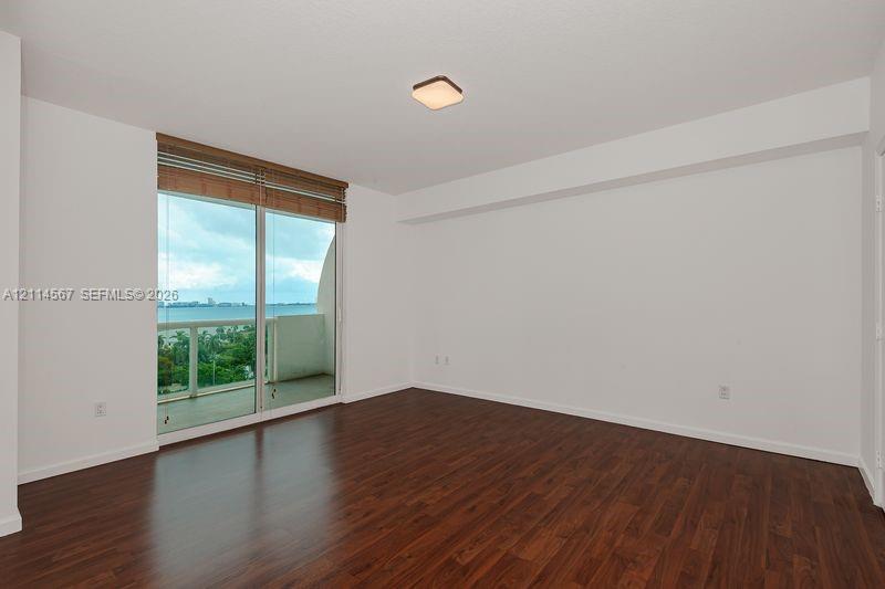 Interior space featuring dark wood-finish flooring, floor-to-ceiling sliding glass doors, integrated window blinds, and a neutral palette