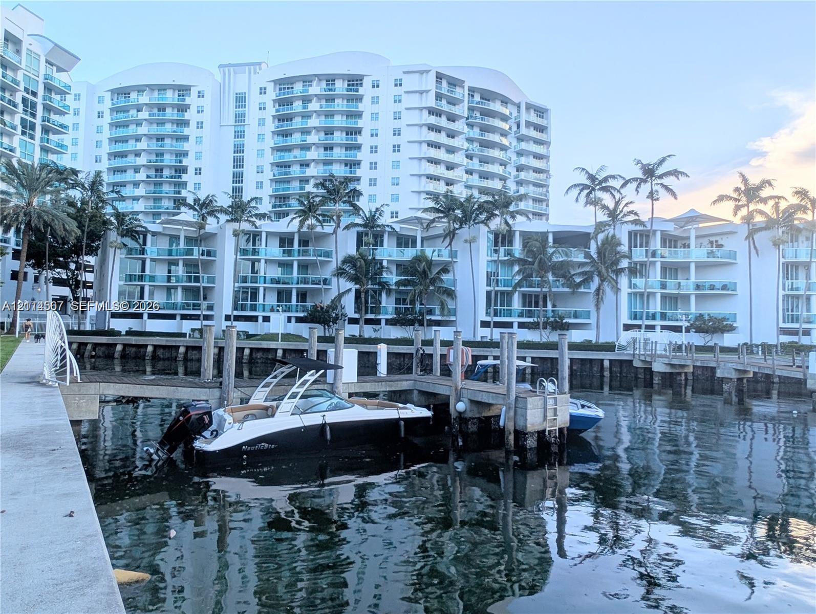 Waterfront high-rise building featuring private deep-water dockage, tiered balconies with glass railings, and mature palm landscaping