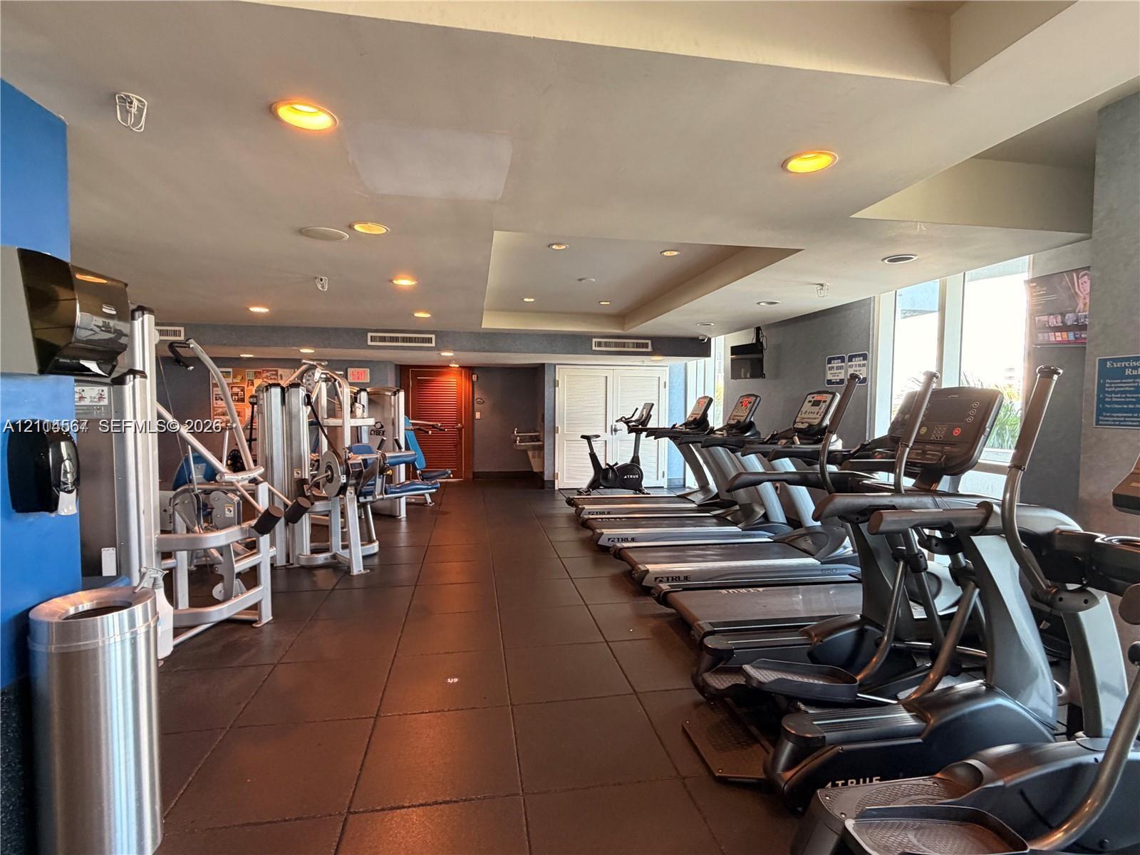 Fitness center featuring rubber flooring, recessed ceiling lighting, and floor-to-ceiling windows