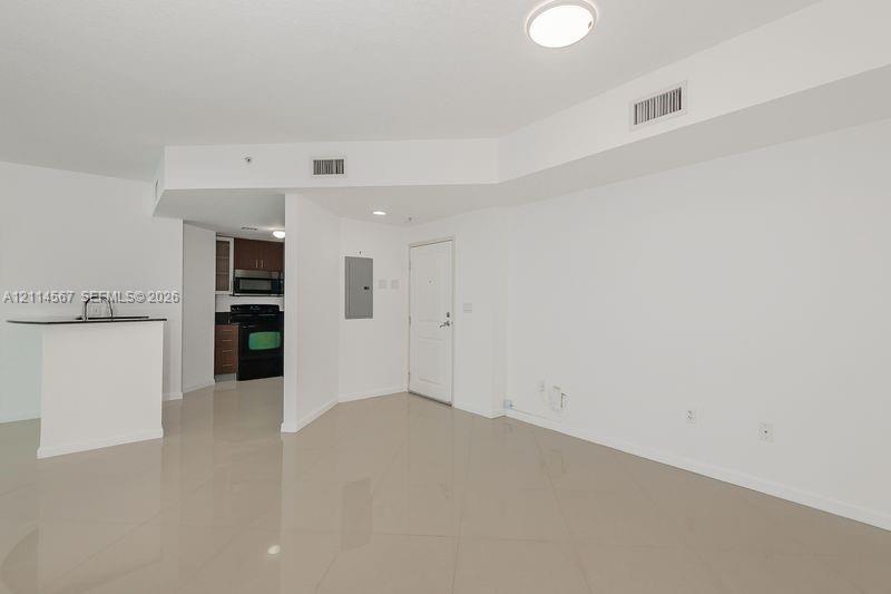 Large-format tile flooring, kitchen peninsula with a dark countertop, recessed ceiling lighting, and solid-core entry door