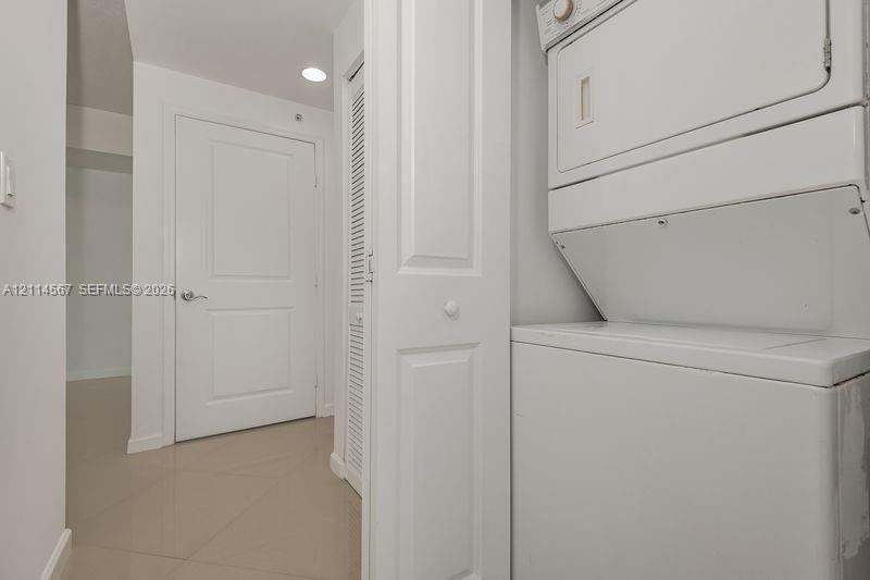 Stacked laundry unit, louvered bi-fold closet door, recessed lighting, and panel-style interior door