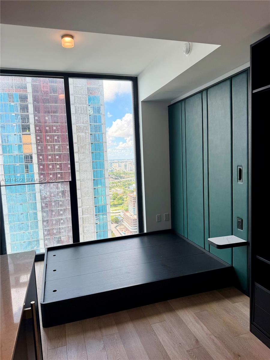 Floor-to-ceiling windows, custom green paneled wall with integrated shelving, built-in elevated platform, and wood-finish flooring