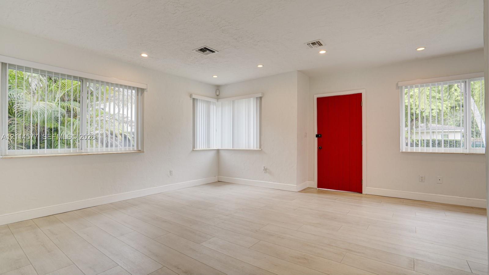 Neutral walls paired with light-toned wood-finish flooring, recessed lighting, and vertical window blinds