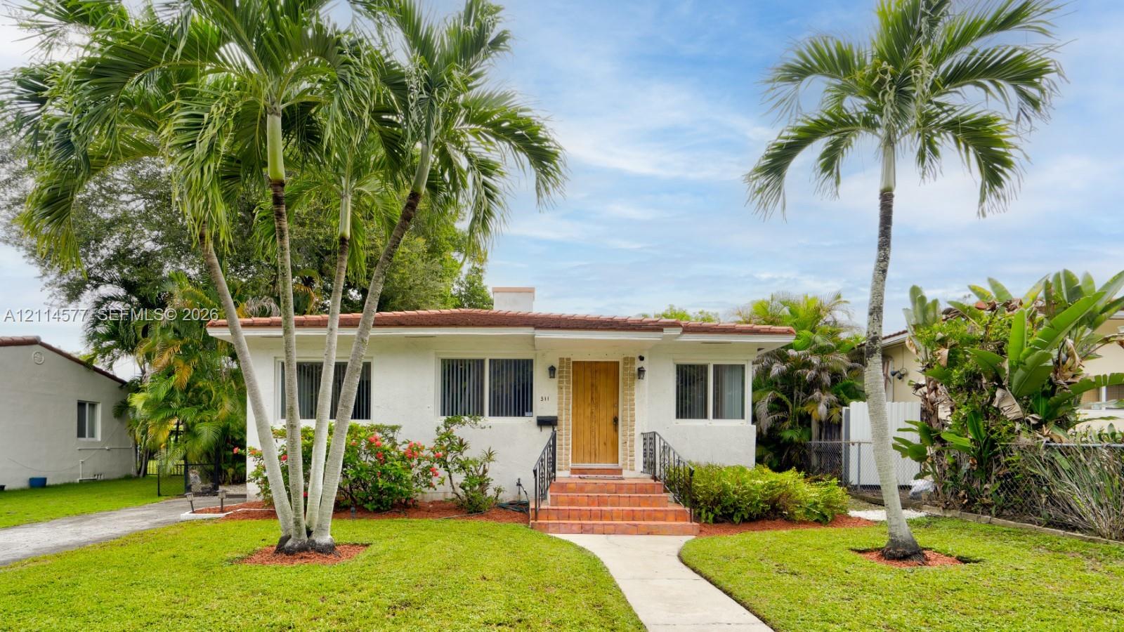 Single-story exterior featuring white stucco finish, tile roof, natural wood-finish front door, and tiled entryway steps with metal handrails Single-story exterior featuring white stucco finish, tile roof, natural wood-finish front door, and tiled entryway steps with metal handrails